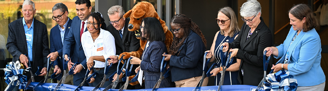 a group of people hold large scissors and cut a ribbon