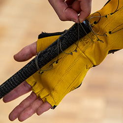 A golf club attaches to a yellow glove via a thin wire that holds it in place